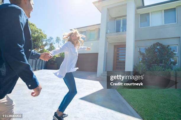 couple joyfully running into their new home. - entrance building people stock pictures, royalty-free photos & images