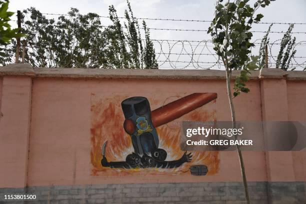 This photo taken on June 2, 2019 shows a propaganda painting depicting a hammer squashing terrorists, on the wall of a military hospital near...