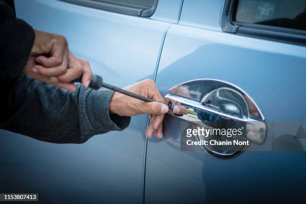 a young man who is breaking into a car - rob photos et images de collection