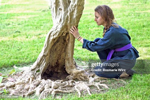 young woman in black kimono touching old tree trunk - charm bracelet - fotografias e filmes do acervo