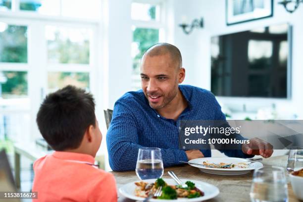 cheerful father listening and smiling towards son - filipino family dinner stock-fotos und bilder