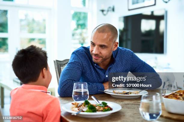 father talking to son at dinner table - filipino family dinner foto e immagini stock