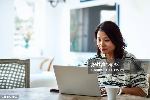 woman using laptop and working from home - asian finance photos et images de collection