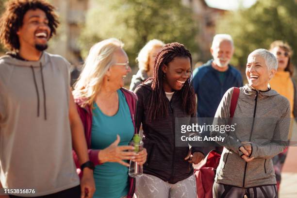 smiling group of people walking together outdoors - baby boomer stock pictures, royalty-free photos & images