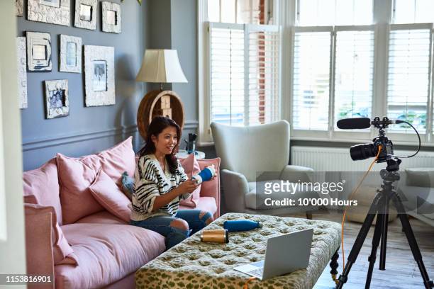 woman vlogging with camcorder showing various drinks bottles - broadcasting house stock pictures, royalty-free photos & images