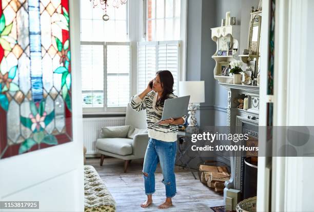 Concerned woman in her 30s on phone with laptop