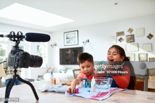 girl squishing blue gloop in hands and laughing - schleim stock-fotos und bilder