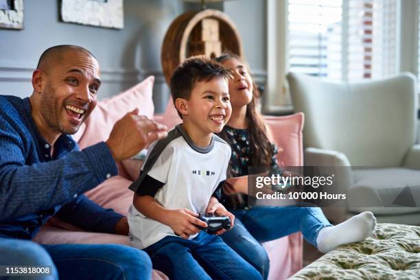 excited father watching son and daughter play video game - game three stockfoto's en -beelden