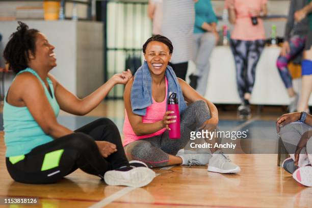 friends sitting on the floor and talking after dance class while drinking water - health club stock pictures, royalty-free photos & images