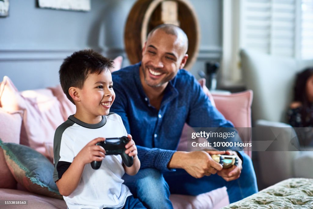 Cheerful father playing games console with son