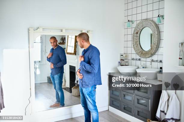mature man checking himself in bathroom mirror and touching tummy - negatieve eigenwaarde stockfoto's en -beelden