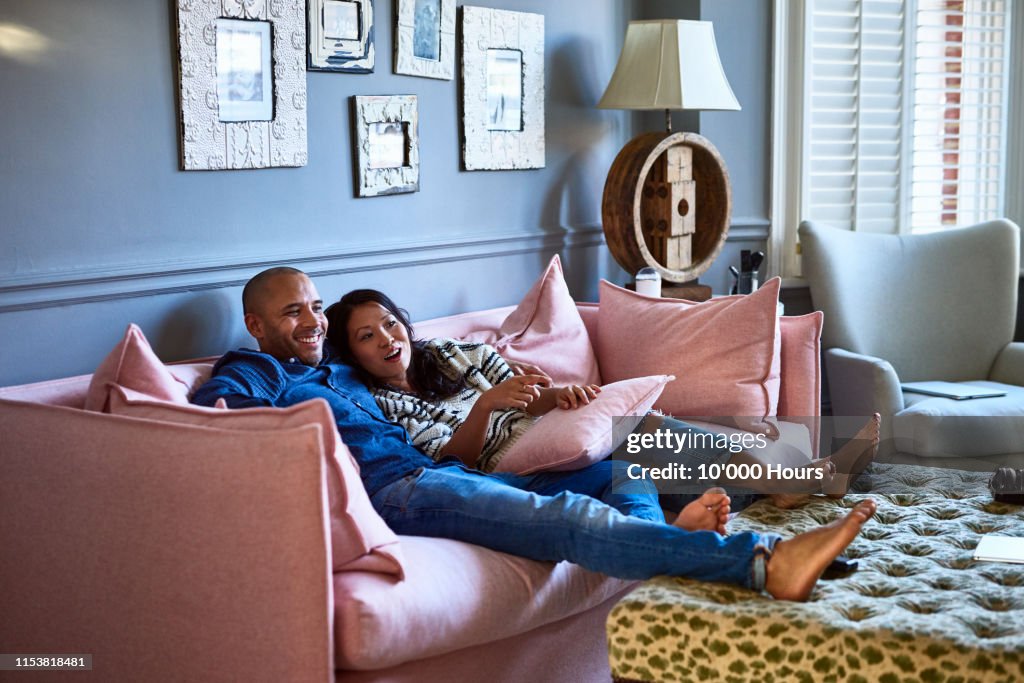 Couple at home watching television together on sofa