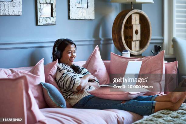 mid adult woman smiling and watching movie on laptop - series stock-fotos und bilder