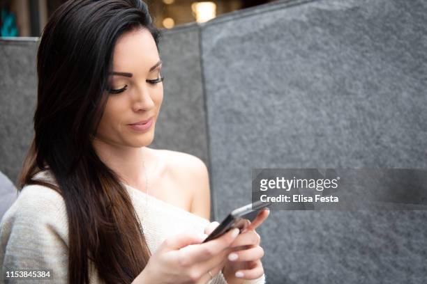 a portrait of a young beautiful woman looking at her mobile phone - fiesta elegante stock-fotos und bilder
