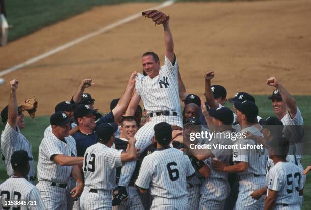 Pitcher David Cone of the New York Yankees celebrates with his team mates after pitching the perfect game during the Major League Baseball American...