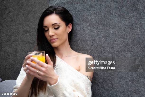 a portrait of a young woman drinking orange juice and smiling - fiesta elegante stock-fotos und bilder