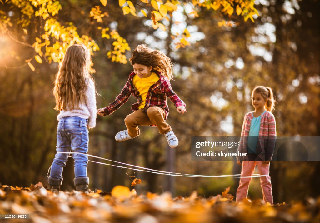 Group of happy girls having fun while playing rubber band game in autumn day.