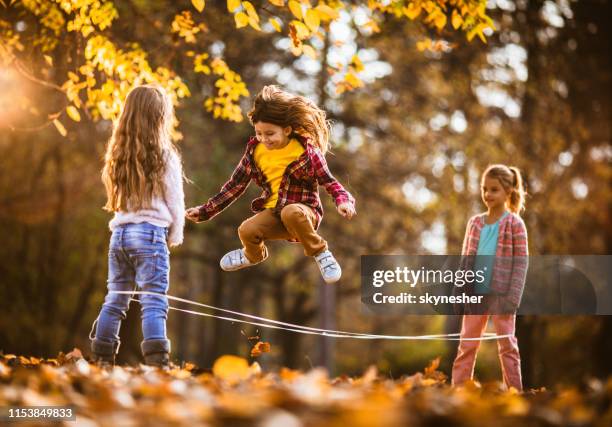 group of happy girls having fun while playing rubber band game in autumn day. - jumping rope stock pictures, royalty-free photos & images