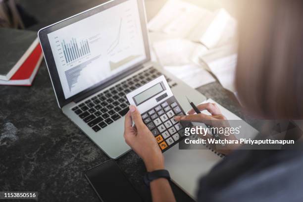 close-up of calculator and coins and asia young wonman analyzing financial data. accounting and financial concept. - accounting calculator stock pictures, royalty-free photos & images