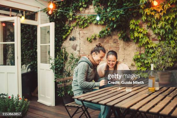 two female friends sitting on terrace. - dachterasse stock-fotos und bilder