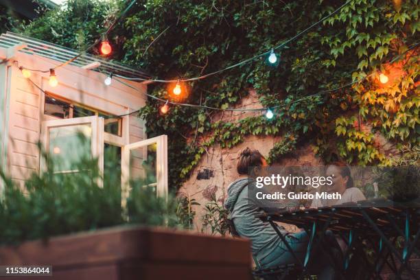 two women sitting on roof garden. - garden lighting stock pictures, royalty-free photos & images