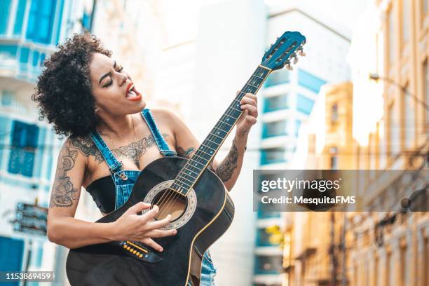 mulher do punk que joga a guitarra acústica - street artist - fotografias e filmes do acervo