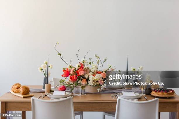 mid century modern beautiful styled pink and wedding flowers on wooden table with place setting and invite - wedding table setting stockfoto's en -beelden