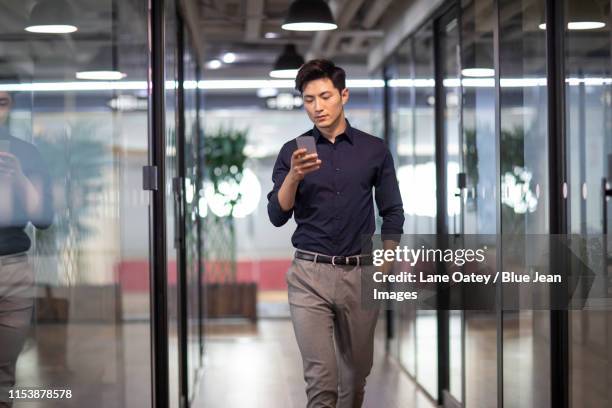 confident young businessman using smart phone - asian man texting ストックフォトと画像