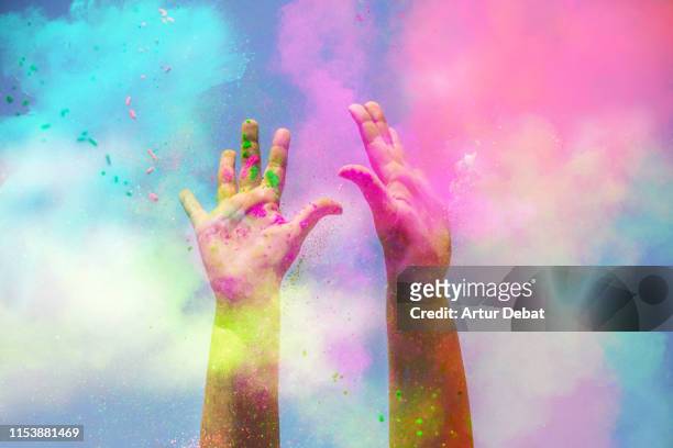 happy girl raising arms with the colorful powder splash during celebration. - color image stockfoto's en -beelden
