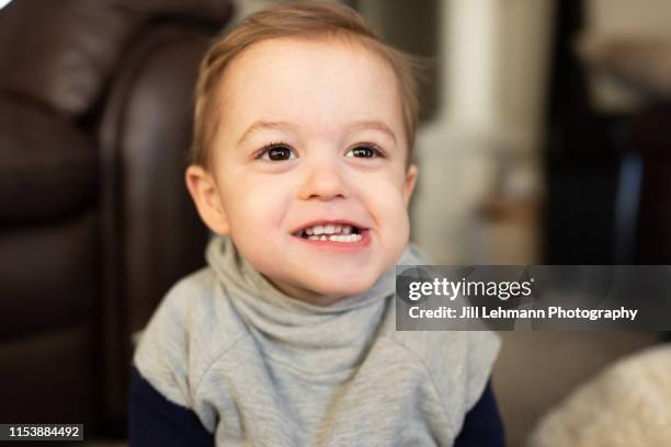 2 year old male toddler has wide crooked smile and looks up and away from camera - old trying to look young stock pictures, royalty-free photos & images