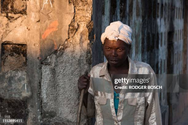 Delfina Graca, part of a group of homeless people living in a building damaged during the Angolan civil war, leans on a walking stick as she talks...