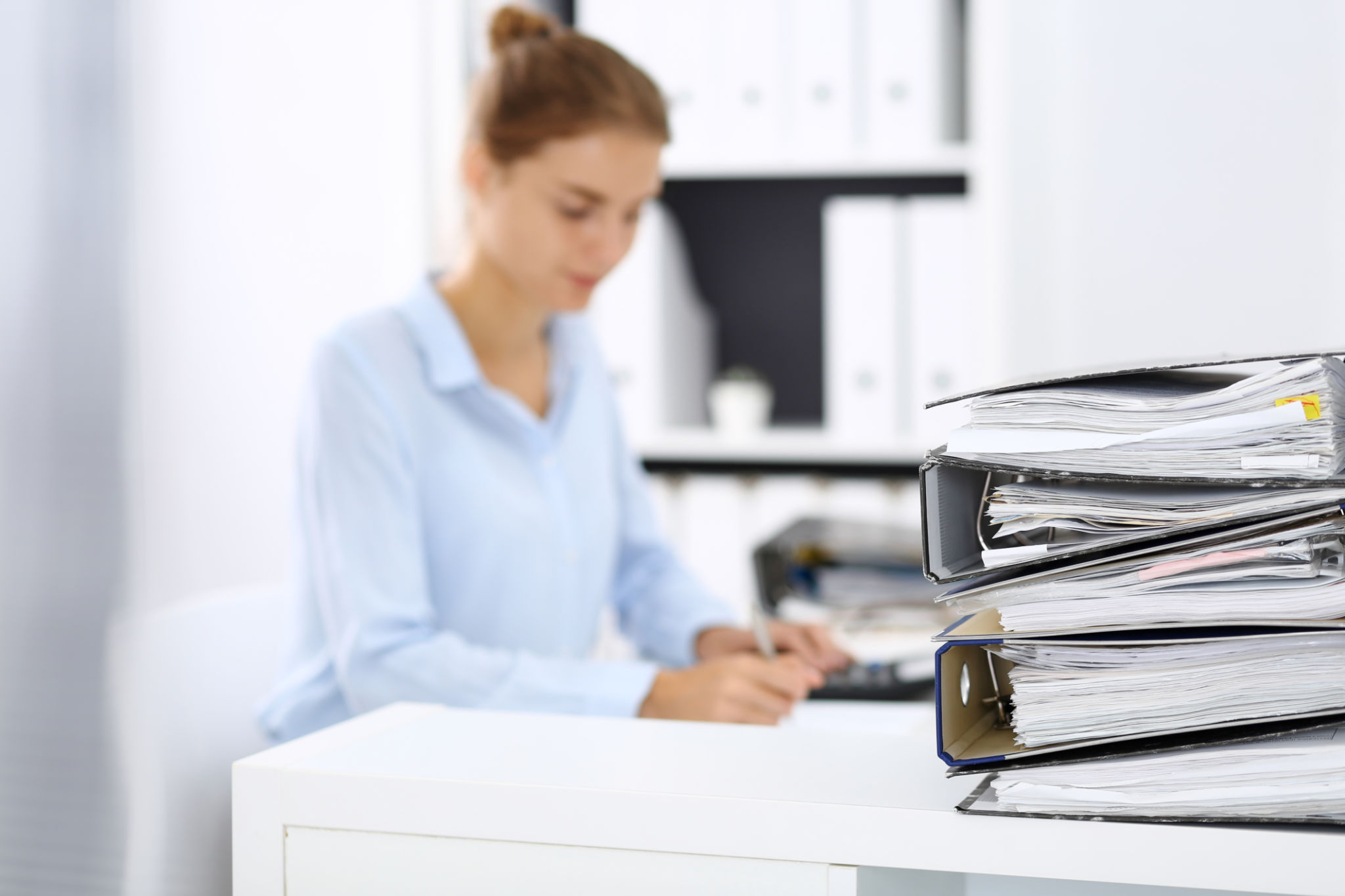 Binders with papers are waiting to be processed by business woman or bookkeeper back in blur. Internal Audit and tax concept Binders with papers are waiting to be processed by business woman or bookkeeper back in blur. Internal Audit and tax concept