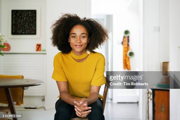 woman sat on chair looking at camera - woman relaxed portrait sitting stockfoto's en -beelden