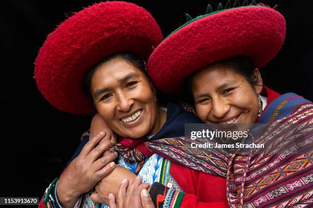 portrait of two local women who are close friends, in colourful, predominantly red, traditional local dress and hats, chinchero, sacred valley, peru (model releases) - latin america stock pictures, royalty-free photos & images