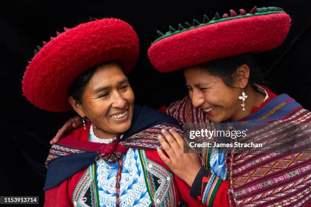 portrait of two local women who are close friends, in colourful, predominantly red, traditional local dress and hats, chinchero, sacred valley, peru (model releases) - urubamba valley stock pictures, royalty-free photos & images