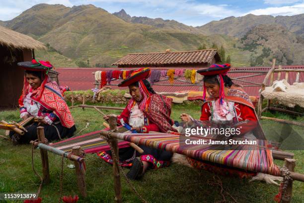three local female weavers in colourful traditional local dress including festooned hats, weaving colourful alpaca wool on the ground, chumbe community, lamay, sacred valley, peru (3 model releases and property release) - perú stock-fotos und bilder