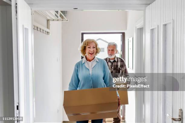 senior couple carrying boxes - senior moving house stock pictures, royalty-free photos & images