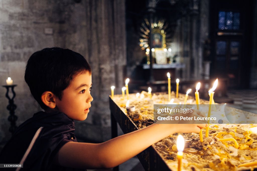 Boy lighting prayer candles