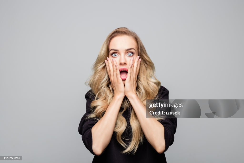 Porträt schockierter junge Frau mit Händen im Gesicht