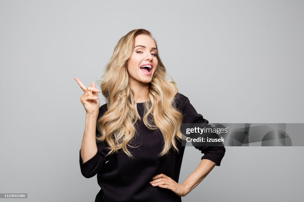 Happy stylist young woman pointing at copy space
