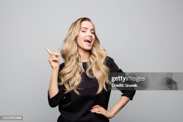 happy stylist young woman pointing at copy space - beautiful woman studio stock pictures, royalty-free photos & images