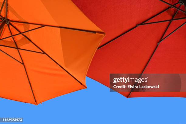 red and orange parasols against clear blue sky - red parasol stock pictures, royalty-free photos & images