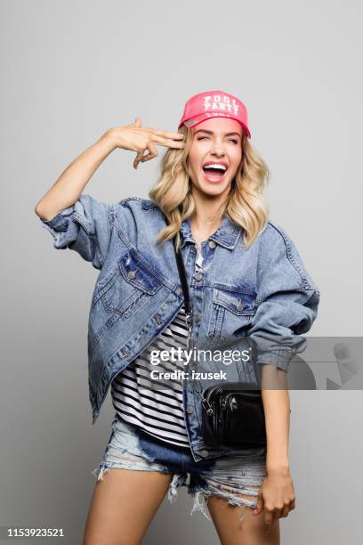 cheerful woman touching her temple with the fingers - denim shorts stock pictures, royalty-free photos & images
