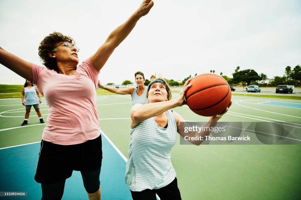 Mature woman waiting to take shot during basketball game on outdoor court