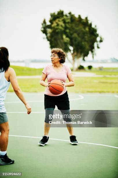 Mature woman looking to make pass during basketball game on outdoor court