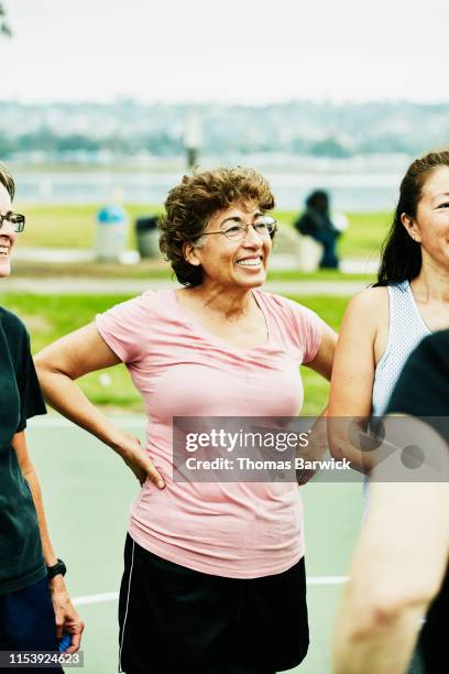 smiling mature woman in discussion with friends after basketball game on outdoor court - mature asian woman candid foto e immagini stock