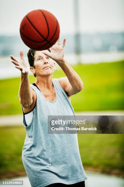 Senior woman catching pass during early morning basketball game