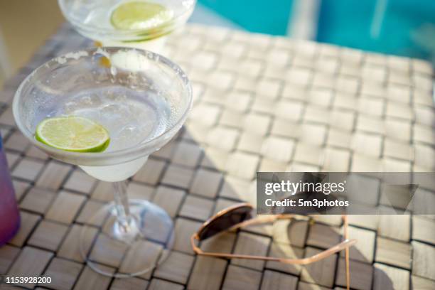 vacation lifestyle sunglasses and alcohol lime drink items at resort pool - margarita beach stock-fotos und bilder