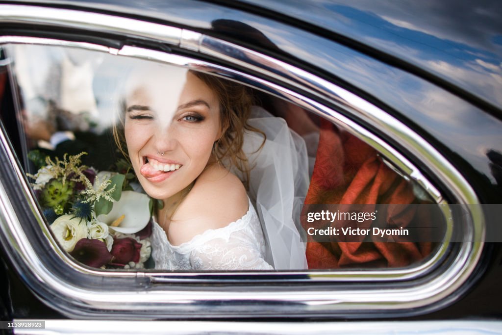Beautiful bride shows tongue sitting in the car