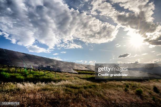 una fattoria solare nel colorado occidentale vicino al tramonto con il sole, il cielo blu e le nuvole che si riflettono sui pannelli solari - pannello di controllo foto e immagini stock